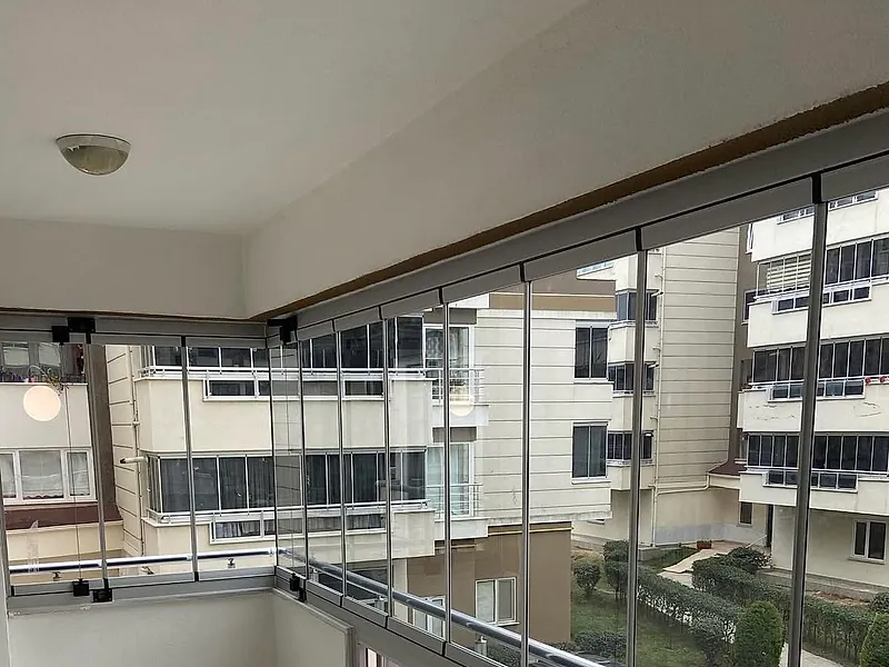 Apartman balkonunda gri profilli sürme cam balkon sistemi, iç mekândan görünüm